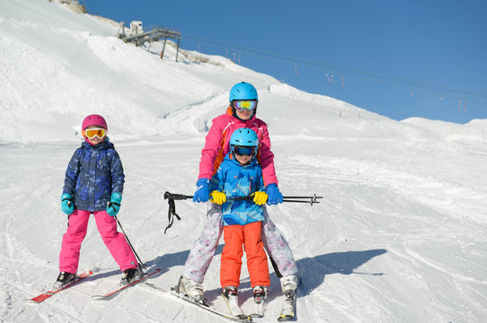 Smiling little boy with family learns skiing during winter vacations.