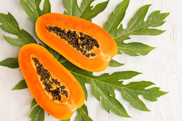 Ripe papaya with green leaf on wooden background.Papaya fruit on wooden background.Slices of sweet papaya on wooden background,Halved papayas with leaves,