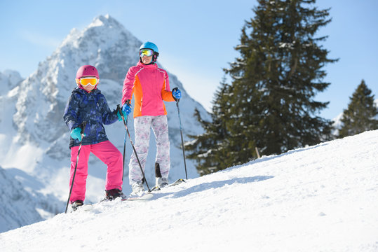 Smiling girl with mother  skiing in Alps mountains. Happy family enjoying winter vacations in mountains . 