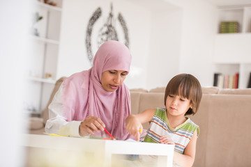 Arabic mother with little son learning in living room