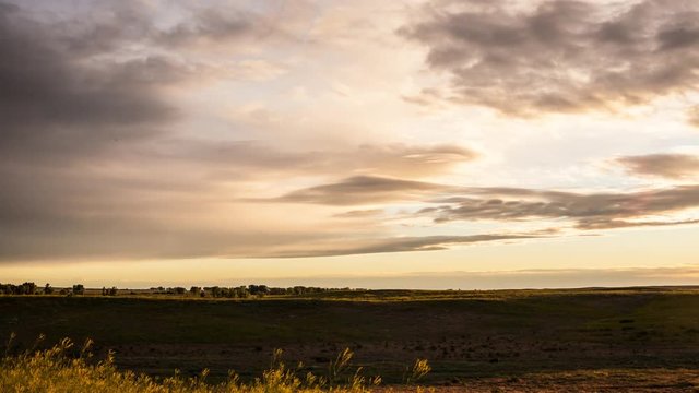 Time lapse - Clouds race to horizon over prairie valley and grasses