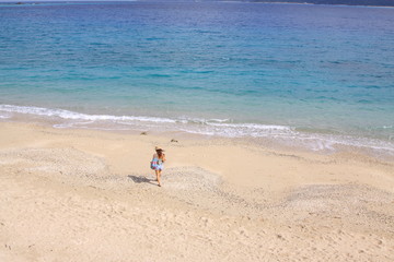 青い海、白い砂浜を歩く女性
