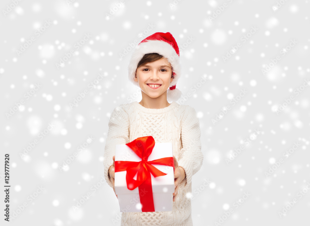 Wall mural smiling happy boy in santa hat with gift box