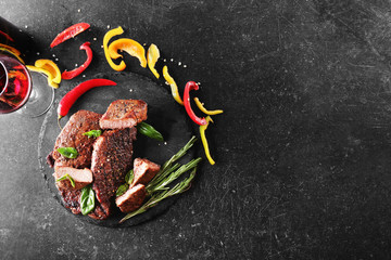Delicious steak with red wine and vegetables on dark background