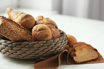 Basket of fresh bread and a slices on a table near the window