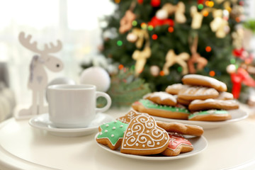 Plate with tasty gingerbread cookies on table against blurred background