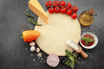 Raw pizza dough with ingredients on table