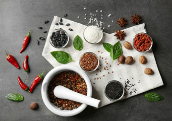 Composition with different spices and mortar on gray background