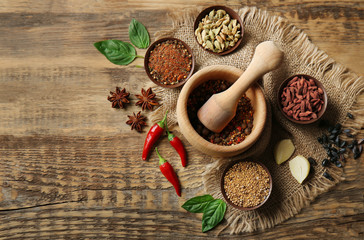 Composition with different spices and mortar on wooden background