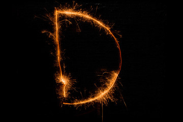 Letter D made of sparklers on black