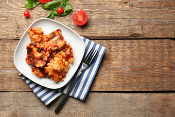 Plate of ravioli with tomato sauce on table