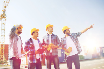 group of smiling builders with tablet pc outdoors