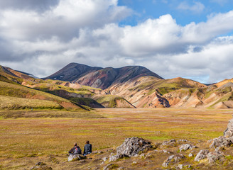 Two hikers admire the dramatic multicoloured mountains at Landma