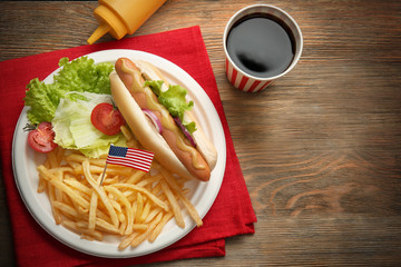Hot dog with french fries and small USA flag on plate