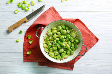 Brussels sprouts in colander with knife on table