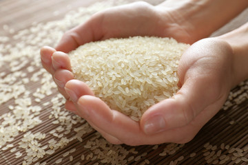 Female hands full of parboiled rice closeup