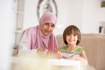 Arabic mother with little son learning in living room