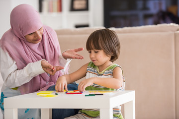 Arabic mother with little son learning in living room