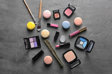 Makeup products and macaroons on grey background