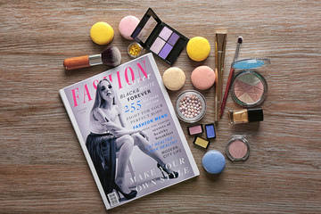 Makeup products, magazine and macaroons on wooden background