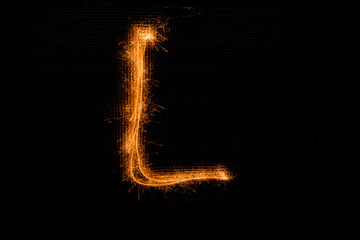 Letter L made of sparklers on black