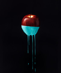 Red apple with dripping blue paint. Minimal food concept.