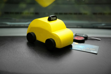 Yellow toy taxi with credit card and key on car dashboard