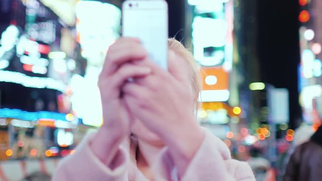 A woman tourist takes pictures of the phone on the famous Time Square in New York City