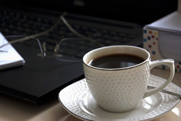 Blank notepad over laptop and coffee cup. Work desk with laptop computer and hot coffee cup with defocused background