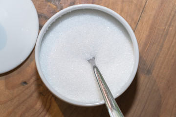 White sugar in glass bowl with teaspoon
