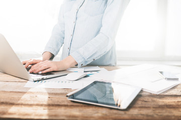 Woman working on a laptop and tablet pc indoor on a wooden stand