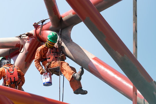 Workers working at height to paint the jack up oil and gas rig