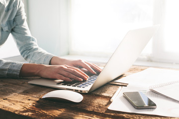 Woman working on a laptop and tablet pc indoor on a wooden stand