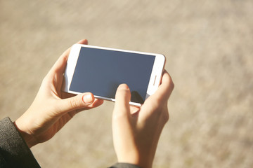 Woman holding modern cellphone, outdoor