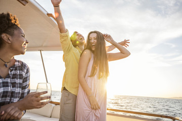 Happy friends having a party on a boat trip