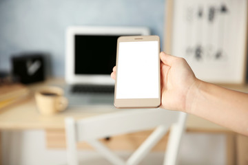 Woman holding modern cellphone at home