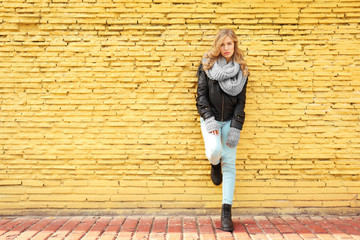 Young beautiful woman standing on yellow brick wall background