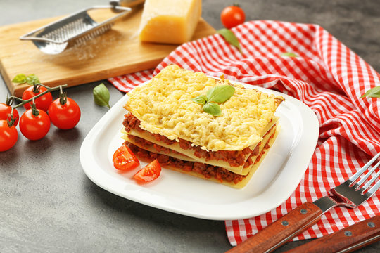 Plate with tasty lasagna on grey table