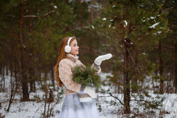 Attractive young girl in wintertime outdoor. A girl in the winter forest smiling and cheering. Snow is falling