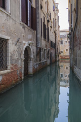 Fototapeta na wymiar Vintage Venetian facades and gates reflects in calm canal water