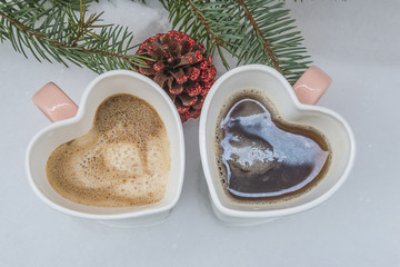 Christmas coffee/Two cup of coffee in form of hearts on snow near fir branch top view