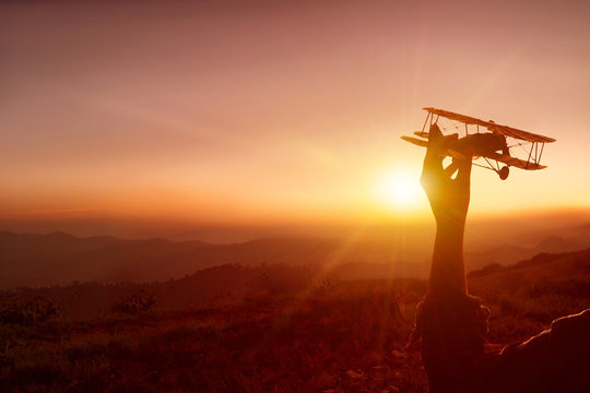 Silhouette Woman hand and toy airplane in the sunset.