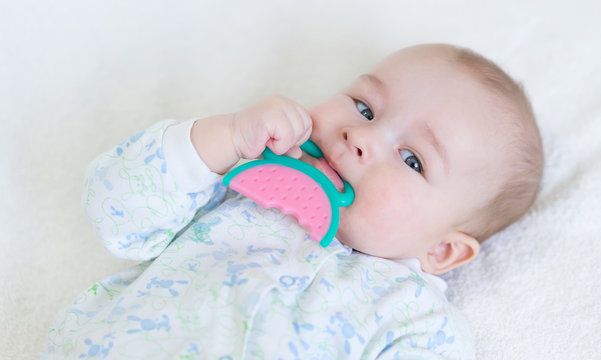 painful teething in infants, baby close-up with a toy.