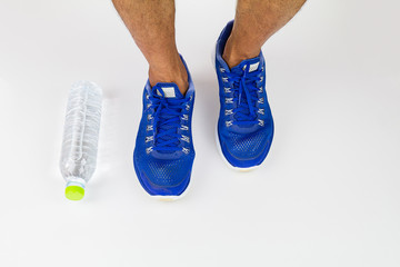 Legs, sport shoes and water bottle on white background