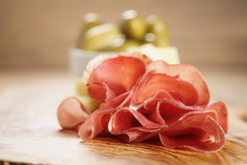 bresaola with parmesan cheese and olives on cutting board, italian antipasti