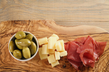 bresaola with parmesan cheese and olives on cutting board, italian antipasti