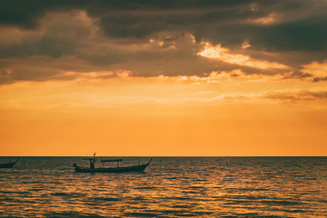 Sunset by The Andaman Sea. Fishing boats pull their nets. Silhouette boat in the sunlight.