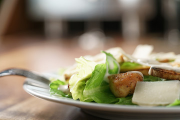 closeup shot of caesar salad with chicken on old wooden table, shallow focus