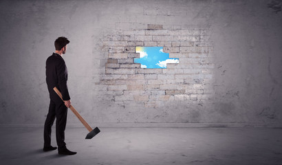 Business man hitting brick wall with hammer