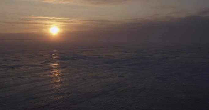 Sun shines off sea ice in blowing snow and storm clouds